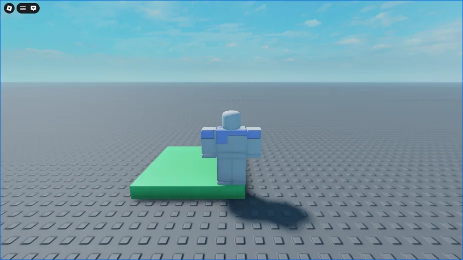 The same view after holding W. The character stands on the near edge of the Pad, which is green now, with its shadow on the baseplate beside it.